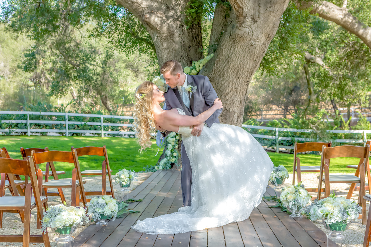 150 year old oak tree, draped with white roses, groom dipping the bride for a kiss